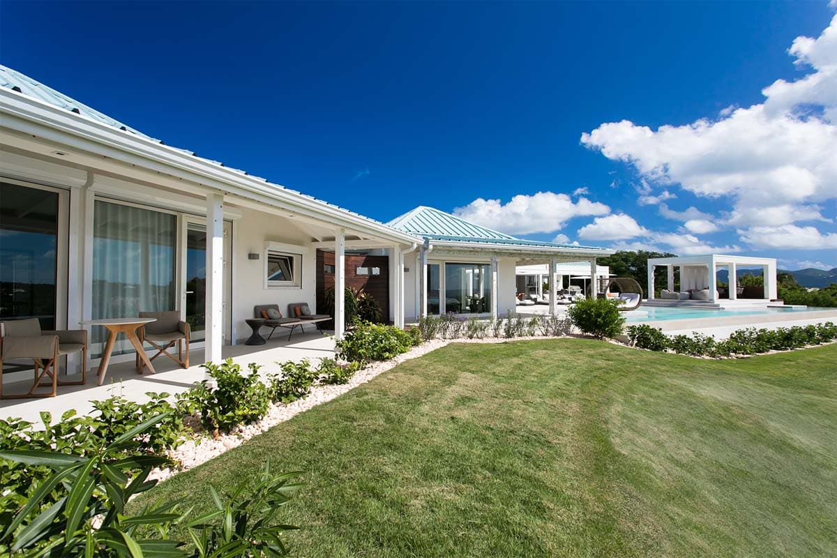 Villa Avanti's exterior featuring lush lawn, ocean views, and modern architecture in Terres Basses, St. Martin