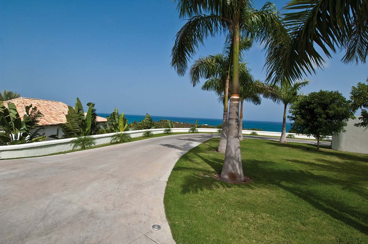 Grand entrance of Sandyline Estate with palm-lined driveway in Terres Basses, St. Martin