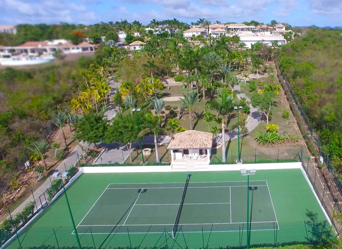 Aerial view of Sandyline Estate in Terres Basses, St. Martin, highlighting the expansive villa layout, tennis pavilion, and lush tropical landscape