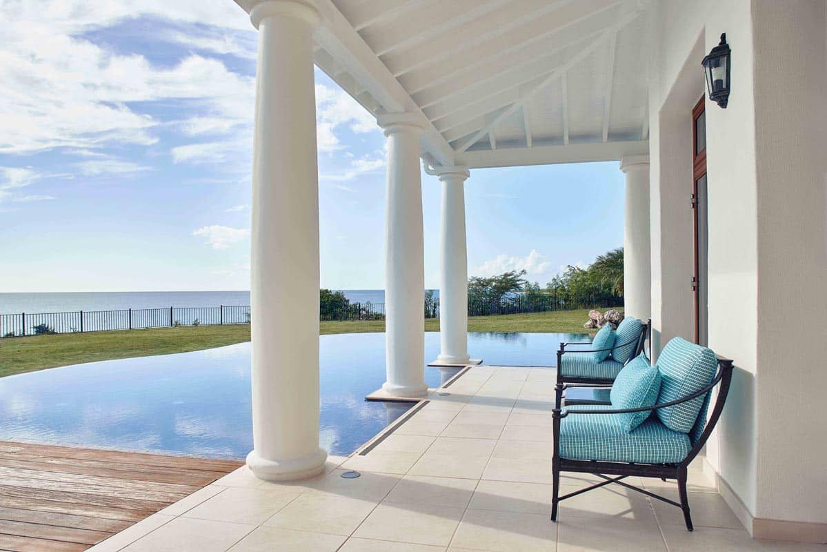 Stone‐clad villa terrace beside pool with palms, luxury resort in St. Maarten