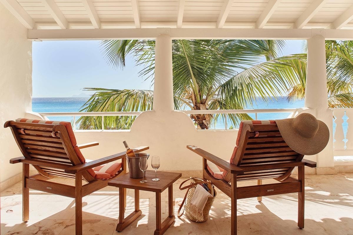 Two-Bedroom Ocean View Suite at Belmond La Samanna, featuring a king-size bed, twin beds, and a private balcony overlooking the Caribbean Sea.