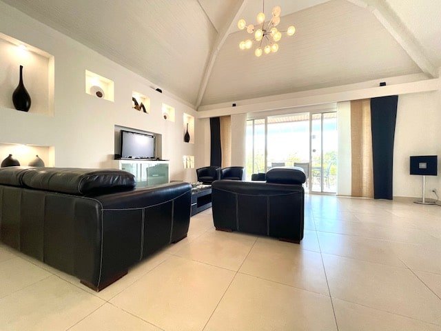 Contemporary living room with black leather seating and smart TV at Villa Paloma, Orient Bay, St. Martin.