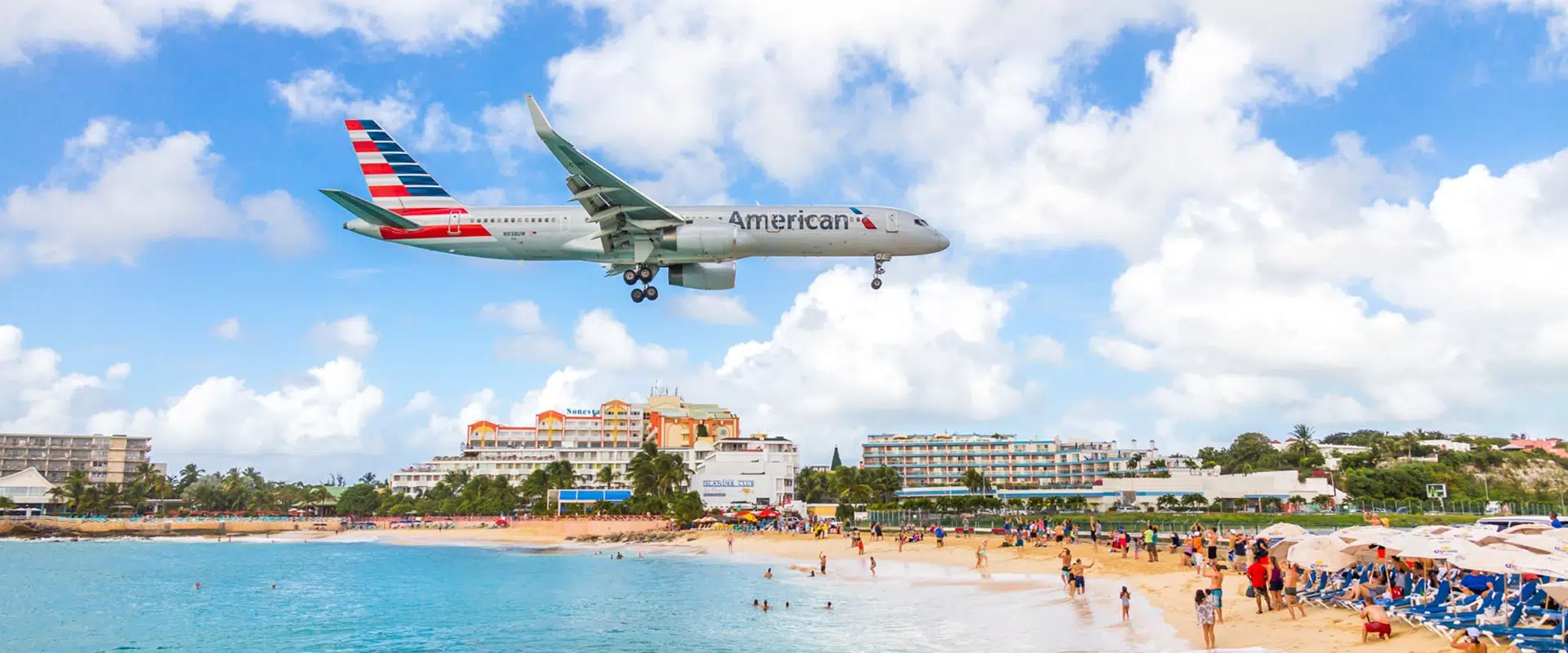 A vibrant sunset over Maho Beach, with a silhouette of an aircraft descending towards Princess Juliana International Airport.