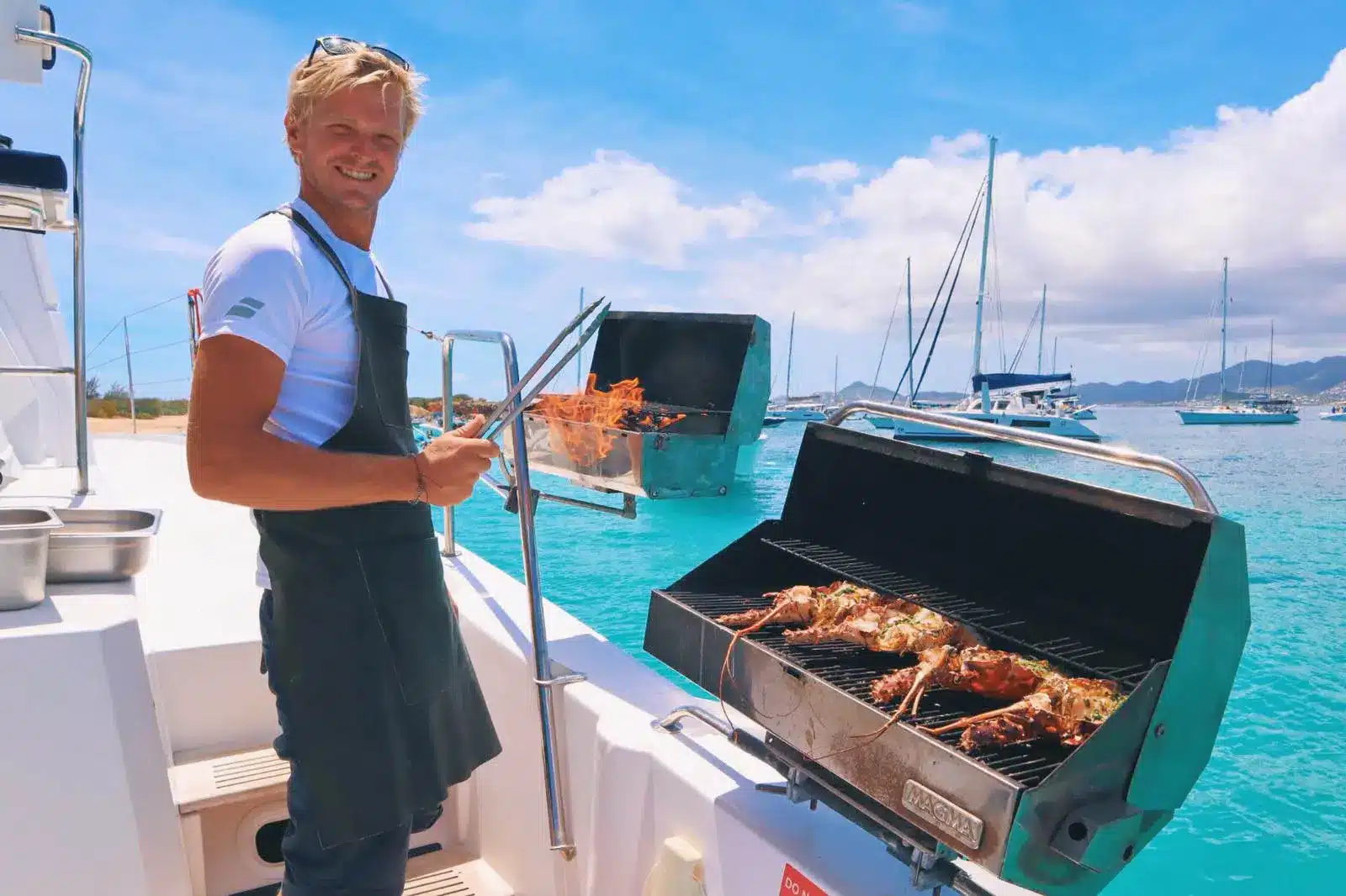 Captain grilling BBQ lobster aboard Ever Glorious catamaran near St. Maarten waters