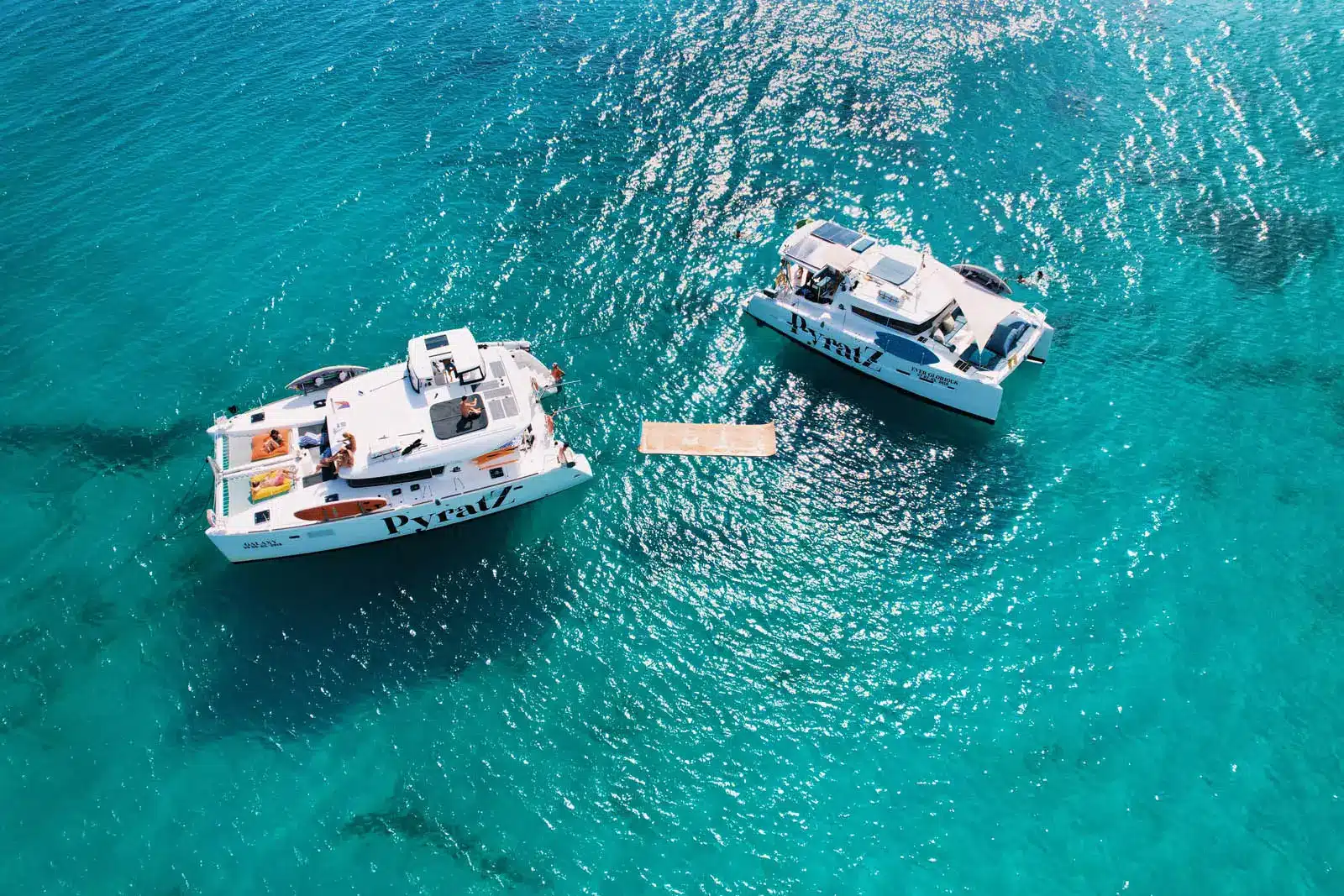 Two luxury catamarans moored side by side in clear St. Maarten turquoise waters