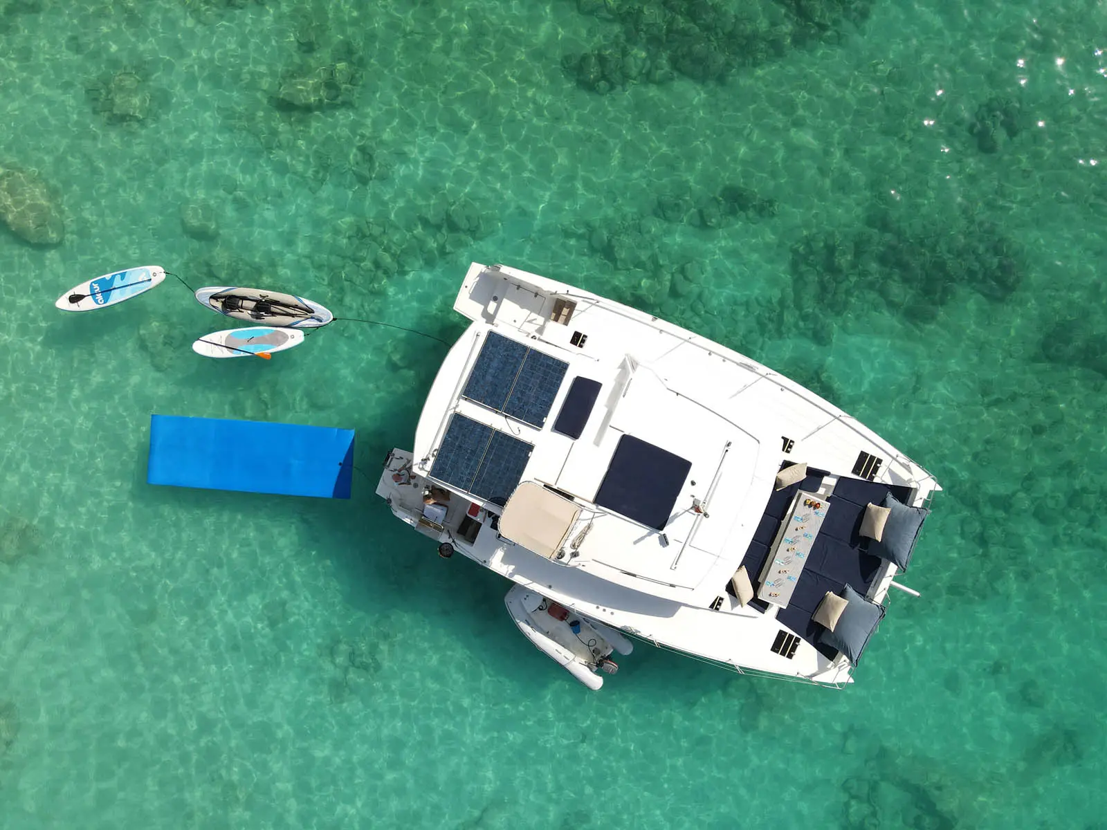Lagoon 450S power catamaran 'Galaxy' anchored in turquoise waters off St. Maarten, showcasing paddle boards, a kayak, and a floating mat